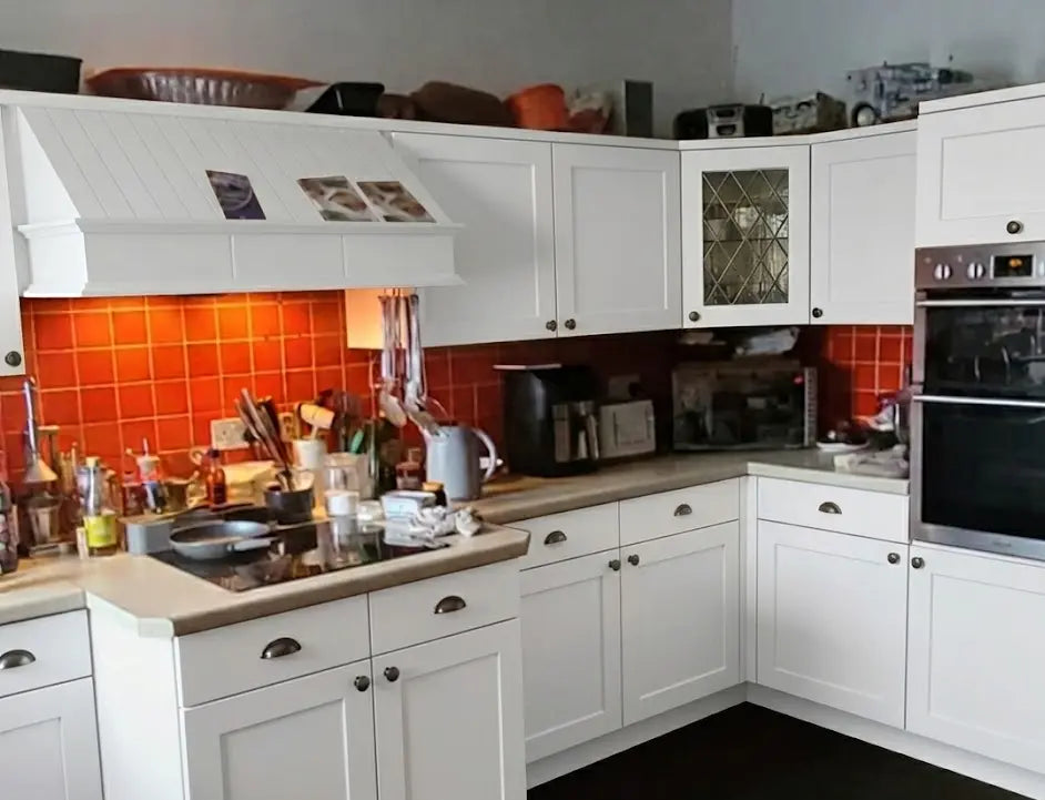 After visualization of the same L-shaped kitchen showing a modern transformation, featuring new bright white shaker kitchen doors and drawers with small knobs.