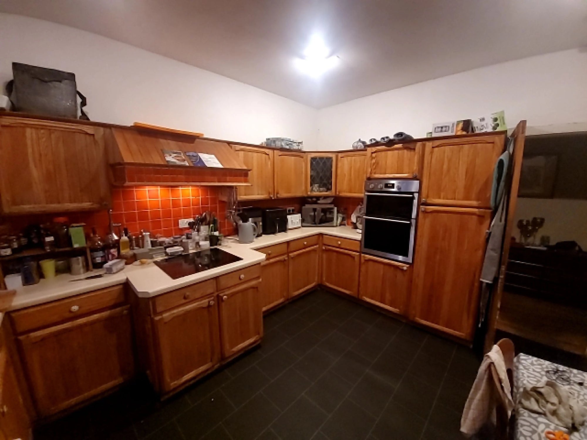 Kitchen with wooden cabinets, appliances, and tiled floor.